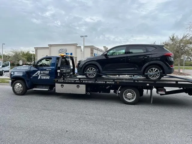 Navy Action Towing flatbed carrying a black SUV