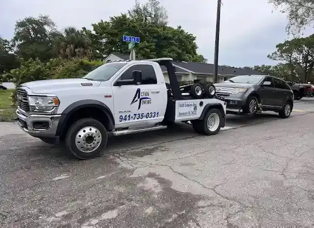 Action Towing wrecker towing a pickup from an apartment community parking lot