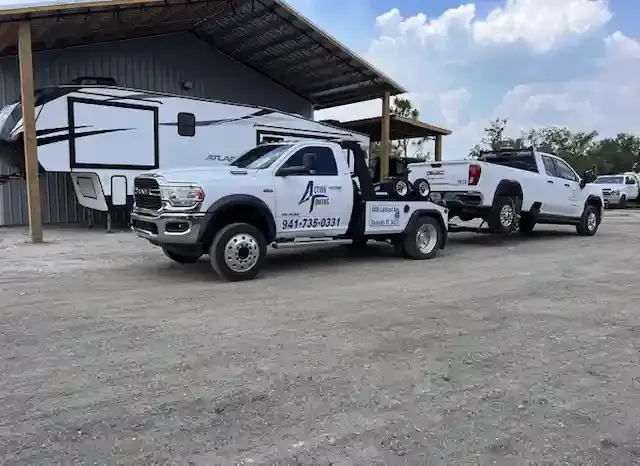 Action Towing wrecker removing a white pickup from a covered RV storage lot